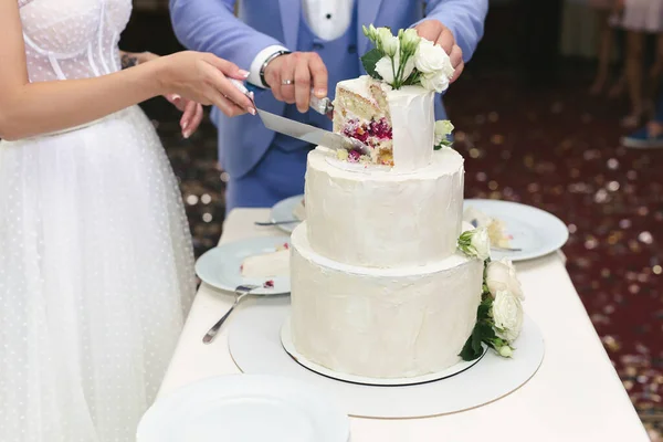 Panna młoda i pan młody pokroili wspaniały tort weselny na bankiecie — Zdjęcie stockowe