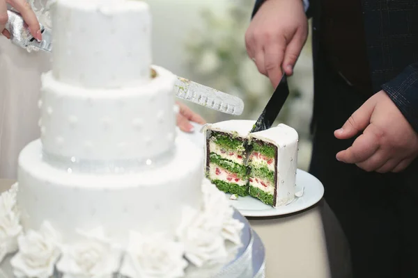 La novia y el novio cortaron un hermoso pastel de bodas en un banquete — Foto de Stock