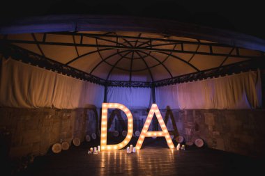 Gelin ve damadın ahşap baş harfleri ve düğünde parlak ışıklar.