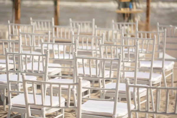 Spazio esterno per cerimonie in spiaggia con vista mare, sedie bianche, arco floreale in una giornata di sole. — Foto Stock