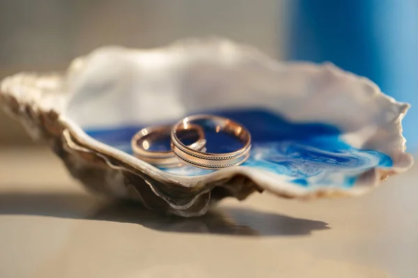 Close-up widok obrączki w muszli na stole z wystrojem ślubnym na ceremonii ślubnej na plaży — Zdjęcie stockowe