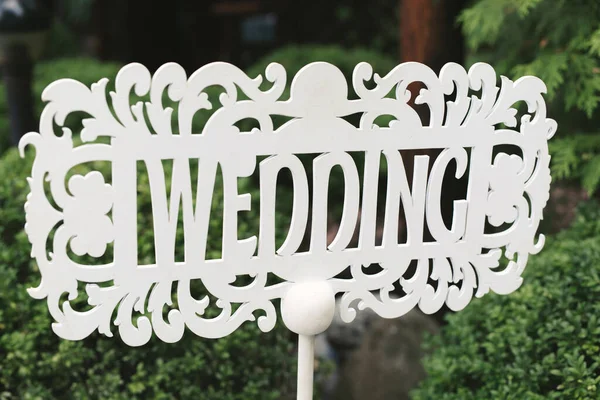 영어로 결혼식이란 글자와 비문이 새겨진 화살 과 포인터의 형태로 흰색 나무로 된 표가 결혼식에서 자연스럽게 서 있다 — 스톡 사진