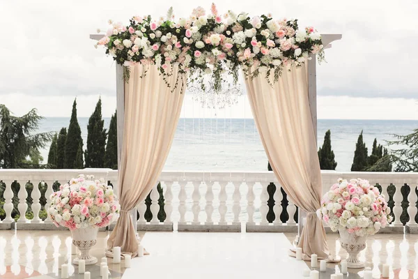 Bröllopsbågen dekorerad med blommor står i det lyxiga området av bröllopsceremonin — Stockfoto