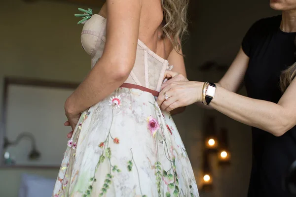 Eine Frau hilft der Braut, ein Hochzeitskleid anzuziehen. — Stockfoto