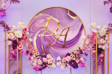 Gelin, damat ve çiçeklerin baş harfleriyle düğün dekoru.