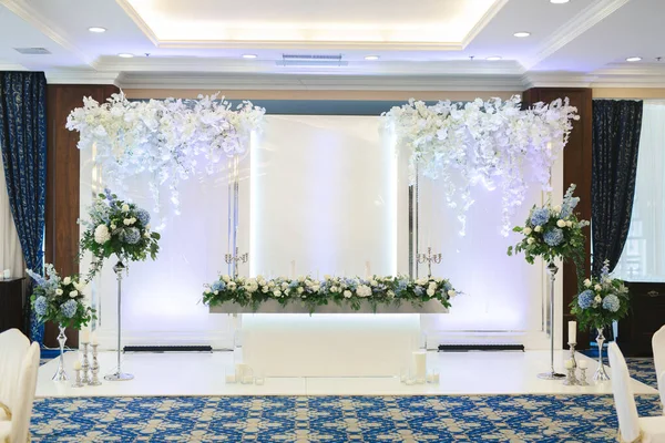 Una pared decorada con las iniciales del nombre y flores cerca de la mesa de comedor de la boda. — Foto de Stock