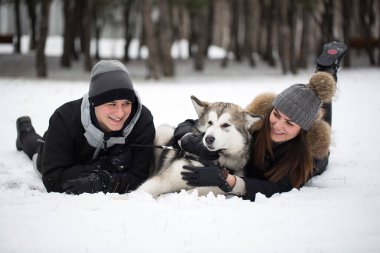 Hoş bir aile, bir erkek ve bir kız ile köpek kış ormandaki. Sibirya husky köpek ile oynamak