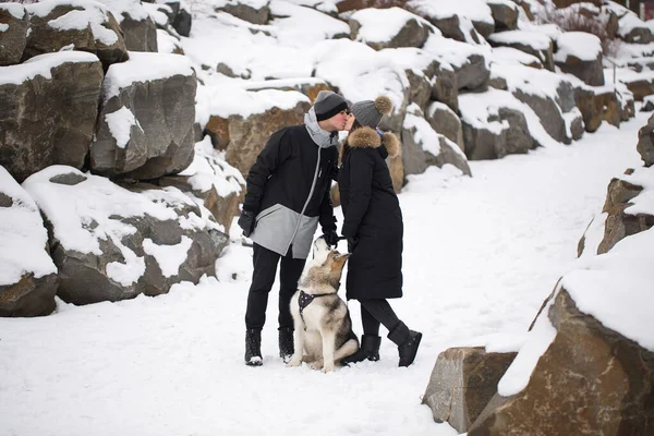 Bela família, um homem e uma menina na floresta de inverno com cão. Brincar com o cão Siberian husky — Fotografia de Stock