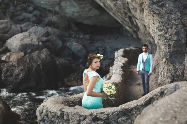 A noiva e o noivo na natureza nas montanhas perto da água. Terno e vestido Tiffany cor. Beijo e abraço — Fotografia de Stock