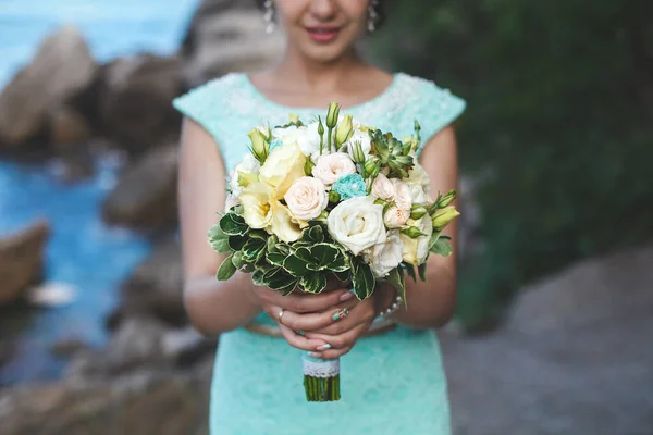 新娘在大自然的山上靠近水。衣服的颜色Tiffany 。新娘拿着花束摆姿势 — 图库照片