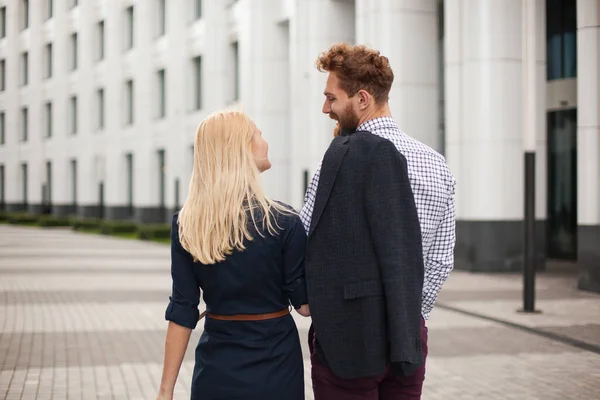 Rückansicht eines jungen Paares, Mann und Frau, die sich anschauen. Das weiße Gebäude im Hintergrund — Stockfoto