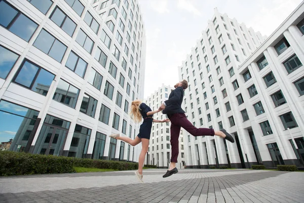 Mann und Frau springen auf den Hintergrund des Gebäudes des Geschäftszentrums — Stockfoto