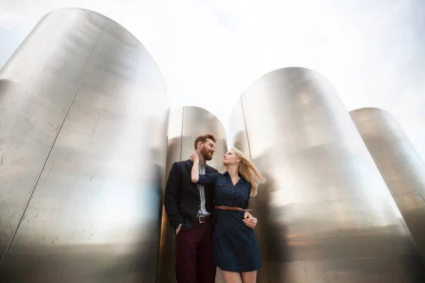 Muž a žena pózují před velkými kovovými trubkami. — Stock fotografie