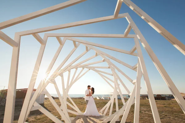 Muž a žena pózují. Geometrické dřevěné konstrukce. Nevěsta a ženich — Stock fotografie