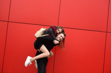 Mutlu insanlar kırmızı bir duvarın arkasında zıplarlar..