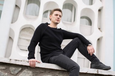 Beyaz arka planda siyah elbiseli, modacı genç adam..