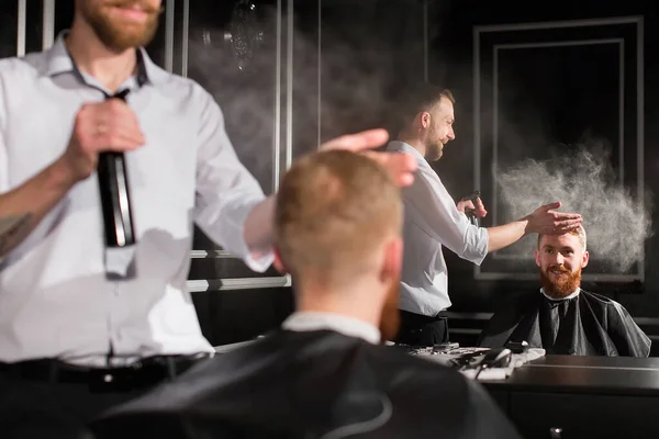 Saç spreyi. Bir berberin portresi müşterinin saçına su püskürtüyor.. — Stok fotoğraf