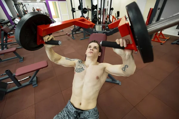 Homem fazendo exercícios no peito na máquina de supino vertical. — Fotografia de Stock