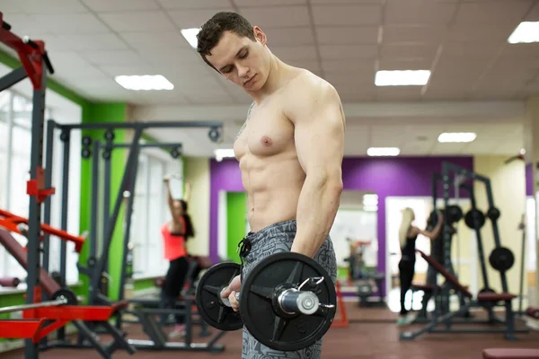 Spierman aan het sporten in de sportschool doet oefeningen met lange halter, sterke mannelijke naakte romp buikspieren. — Stockfoto