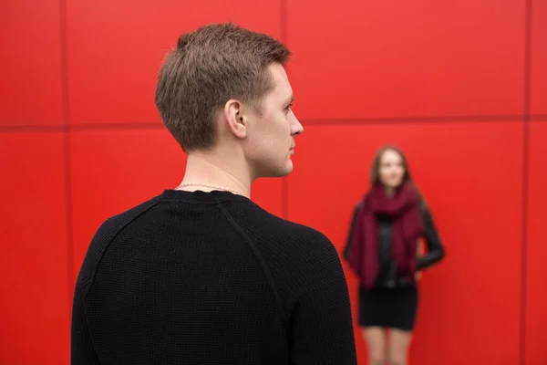 Joven hombre y mujer en pasión, emoción, en la calle con un telón de fondo de la pared roja. Moda . — Foto de Stock