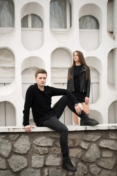 Junges sexy Paar in schwarzer Kleidung posiert mit einem Hintergrund auf der weißen Wand. — Stockfoto
