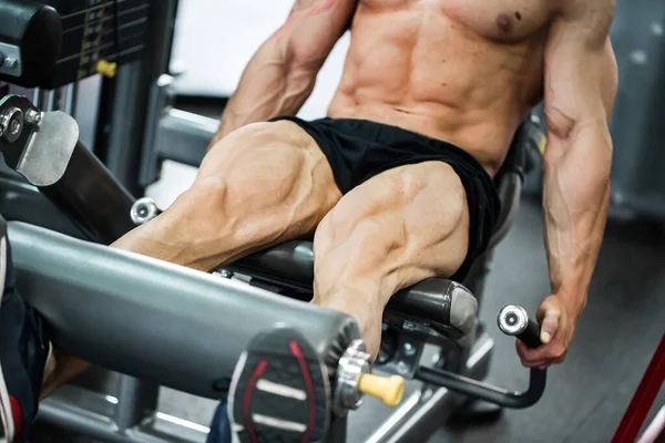 Gimnasio gimnasio interior con pesos de entrenamiento de hombre joven con piernas. — Foto de Stock