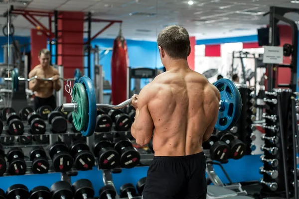 Velmi silný atletický chlap stojící cvičení v tělocvičně. — Stock fotografie