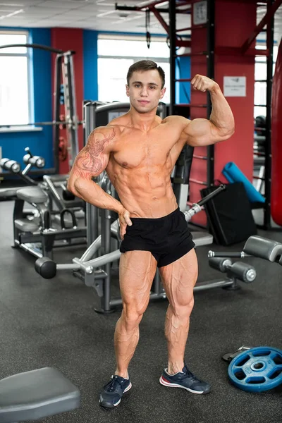 Bodybuilder posant pour la caméra dans la salle de gym. — Photo