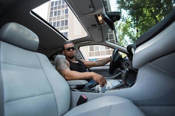 Stijlvolle zwarte man zit achter het stuur van luxe auto — Stockfoto