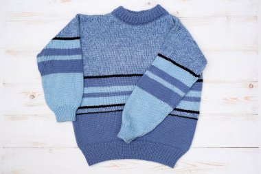 Beyaz arka planda örülmüş çocuk süveteri.