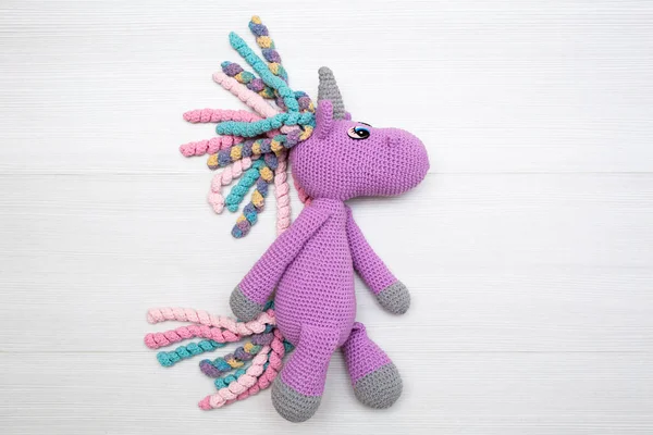 Un unicorno lavorato a maglia con una criniera multicolore. Un giocattolo per un bambino — Foto Stock