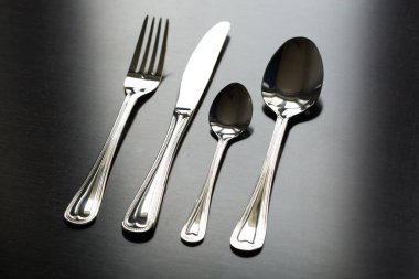 Siyah arka planda çatal bıçak takımı. Çatal, kaşık, bıçak