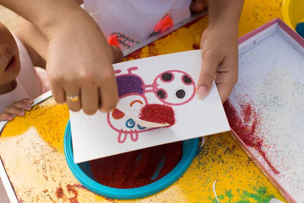 Ребенок рисует цветным песком. Персонажи мультфильмов — стоковое фото