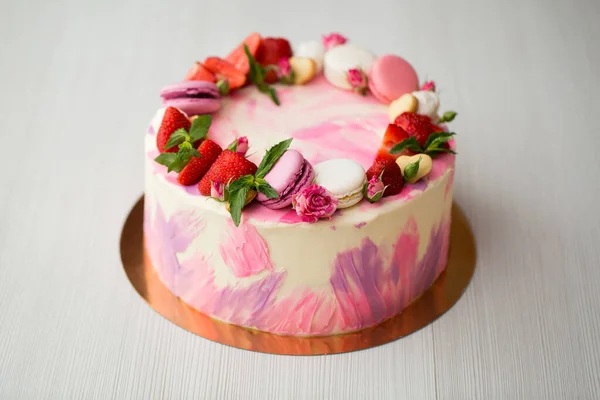 Schöne Torte mit Erdbeeren und Makronen auf einem weißen Tisch. — Stockfoto