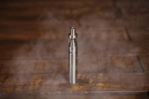 Electronic cigarette on a wooden table. Smoke