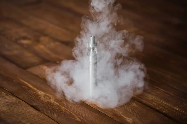 Electronic cigarette on a wooden table. Smoke — Stock Photo, Image