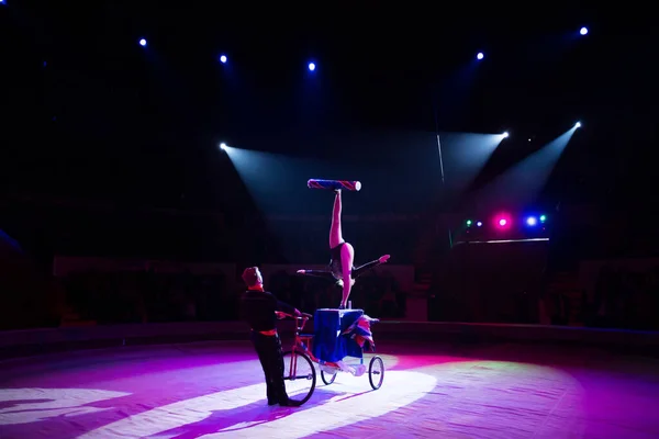 Een jongleur op een fiets onder de koepel van het circus. — Stockfoto