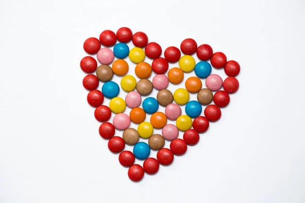 Bonbons au chocolat bouton coloré en forme d'amour sur fond blanc . — Photo