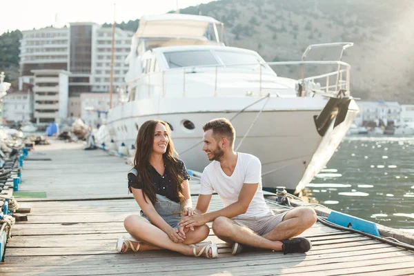 Guy e menina, estão sentados em um cais de madeira. — Fotografia de Stock