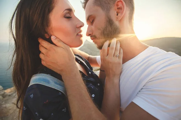 Gli amanti ragazzo e ragazza abbraccio e bacio primo piano sullo sfondo della montagna — Foto Stock