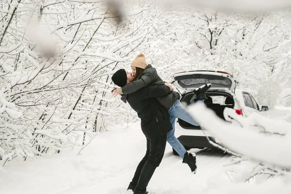 Casal encantador em uma floresta de inverno no fundo de um carro — Fotografia de Stock