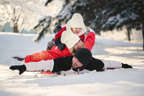 Glada föräldrar och son ligger i snön på vintern i skogen — Stockfoto