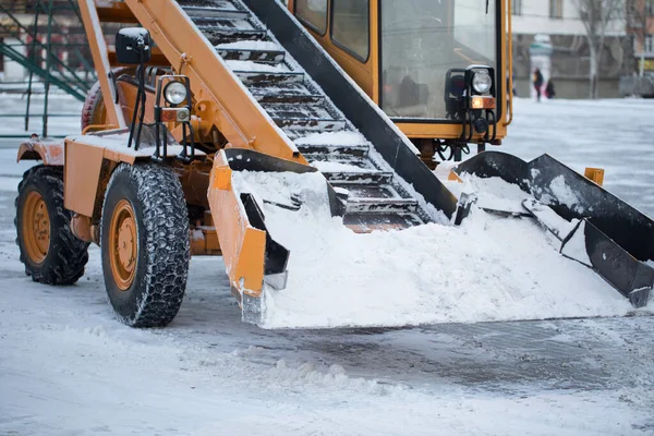 Traktör kardan yolu temizliyor. Kazıcı şehirdeki büyük miktardaki karları temizliyor. — Stok fotoğraf
