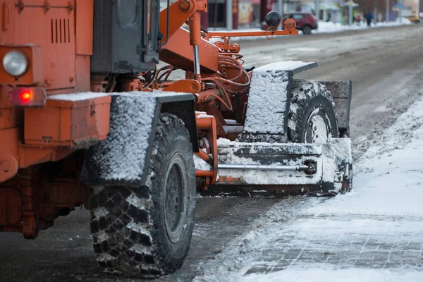Trator limpando a estrada da neve. Escavadeira limpa as ruas de grandes quantidades de neve na cidade. Os trabalhadores varrem a neve da estrada no inverno, limpando a estrada da tempestade de neve — Fotografia de Stock