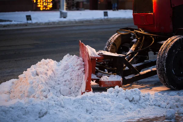 Traktor rengøring vejen fra sneen. Gravemaskine renser gaderne for store mængder sne i byen - Stock-foto
