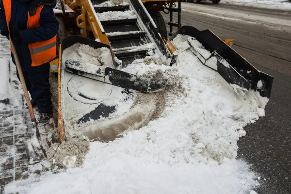 La máquina quitanieves limpia la calle de la nieve. Los trabajadores barren la nieve del camino en invierno, limpiando el camino de la tormenta de nieve — Foto de Stock