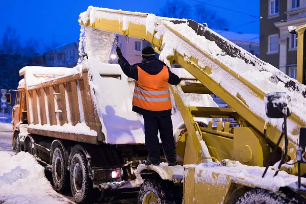 El vehículo cargador de garras elimina la nieve de la carretera. Máquina de quitanieves y camión de nieve limpian las calles de nieve en la ciudad. — Foto de Stock