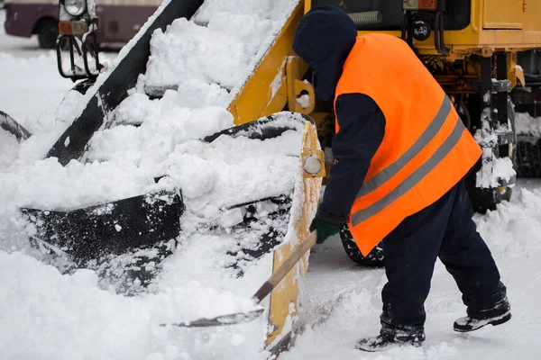 Pençe yükleyici araç karları yoldan çekiyor. Belediye çalışanları kar temizleme aracının içine kar küremeye yardım ediyor — Stok fotoğraf