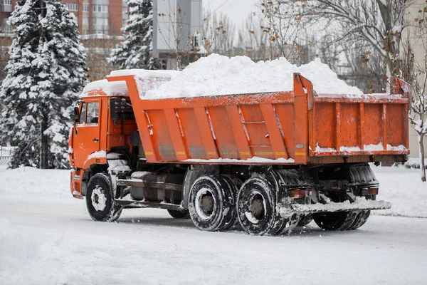 Camião de descarga cheio de neve dirigindo pela rua da cidade, neve transportando. Camião basculante transporta neve para despejar local — Fotografia de Stock