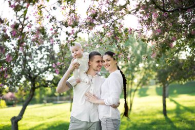 Çocuklu genç bir ailenin portresi. Mutlu bir genç aile yaz günü dışarıda vakit geçirir. Aile yaşamında mutluluk ve uyum. Mutlu aile kavramı